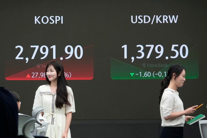 Currency traders pass by the screen showing the Korea Composite Stock Price Index (KOSPI), left, and the foreign exchange rate between U.S. dollar and South Korean won at the foreign exchange dealing room of the KEB Hana Bank headquarters in Seoul, South Korea, Wednesday, June 19, 2024. (AP Photo/Ahn Young-joon)