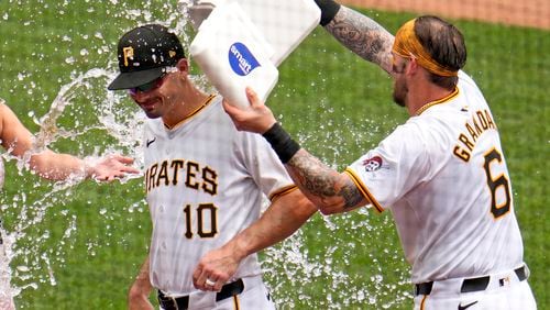 Pittsburgh Pirates' Bryan Reynolds (10) gets doused by Yasmani Grandal (6) as he does a post-game interview following a baseball game against the Cincinnati Reds in Pittsburgh, Wednesday, June 19, 2024. Reynolds hit a solo home run in the eighth inning, leading the Pirates to a 1-0 win. (AP Photo/Gene J. Puskar)