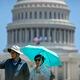 Visitors wear sun hats, sunglasses, and carry an umbrella to protect themselves from the sun as they sightsee near the Capitol in Washington, Wednesday, June 19, 2024. High temperatures are expected to stay in the 90s in the nation's capital for the rest of the week as a heat wave builds into the Northeast. (AP Photo/Mark Schiefelbein)