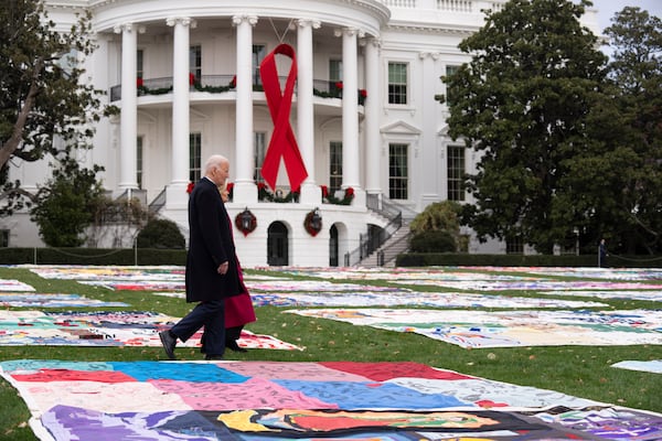 President Joe Biden, left, and first lady Jill Biden walk between AIDS Memorial Quilts spread over the South Lawn at the White House during a ceremony to commemorate World AIDS Day with survivors, their families and advocates, Sunday, Dec. 1, 2024, in Washington. (AP Photo/Manuel Balce Ceneta)