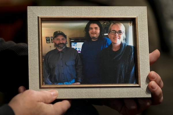 Jerry Barnett holds a picture of, from left, himself; his son, Caimen; and his wife, Sibrina; Nov. 22, 2024, in Johnson City, Tenn. Barnett's wife died trying to escape flood waters caused by Hurricane Helene in September, near the plastics factory where she cleaned offices once a week. (AP Photo/George Walker IV)