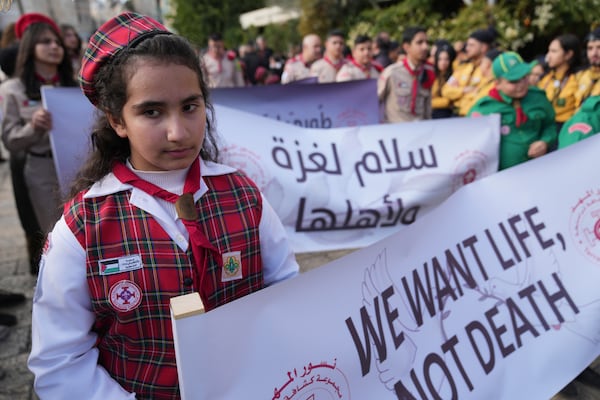 Palestinian scouts carry posters, one reads "Peace for Gaza and its people," while they march during Christmas Eve celebrations at the Church of the Nativity, traditionally recognized by Christians to be the birthplace of Jesus Christ, in the West Bank city of Bethlehem Tuesday, Dec. 24, 2024. (AP Photo/Nasser Nasser)