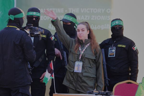 Israeli soldier Agam Beger waves to the crowd next to masked Islamic Jihad militants as she is handed over to the Red Cross at the Jabalya refugee camp in Gaza City, Thursday Jan. 30, 2025.(AP Photo/Mohammed Hajjar)