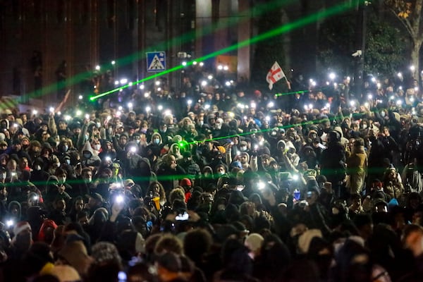 Protesters wave their lights as they are rallying outside the parliament's building to continue protests against the government's decision to suspend negotiations on joining the European Union in Tbilisi, Georgia, on Monday, Dec. 2, 2024.(AP Photo/Zurab Tsertsvadze)