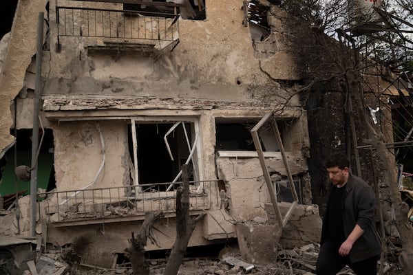 A man walks past a damaged building after a rocket fired from Lebanon hit an area in Rinatya, outskirts of Tel Aviv, Israel, Sunday, Nov. 24, 2024. (AP Photo/Leo Correa)