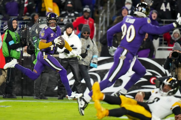 Pittsburgh Steelers quarterback Russell Wilson, bottom right, hits the turf as Baltimore Ravens cornerback Marlon Humphrey, left, returns an interception for a touchdown during the second half of an NFL football game, Saturday, Dec. 21, 2024, in Baltimore. (AP Photo/Stephanie Scarbrough)