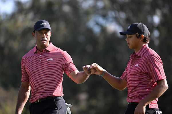 Tiger Woods, left, and his son Charlie Woods fist bump after making their putt on the 13th green during the final round of the PNC Championship golf tournament, Sunday, Dec. 22, 2024, in Orlando, Fla. (AP Photo/Phelan M. Ebenhack)