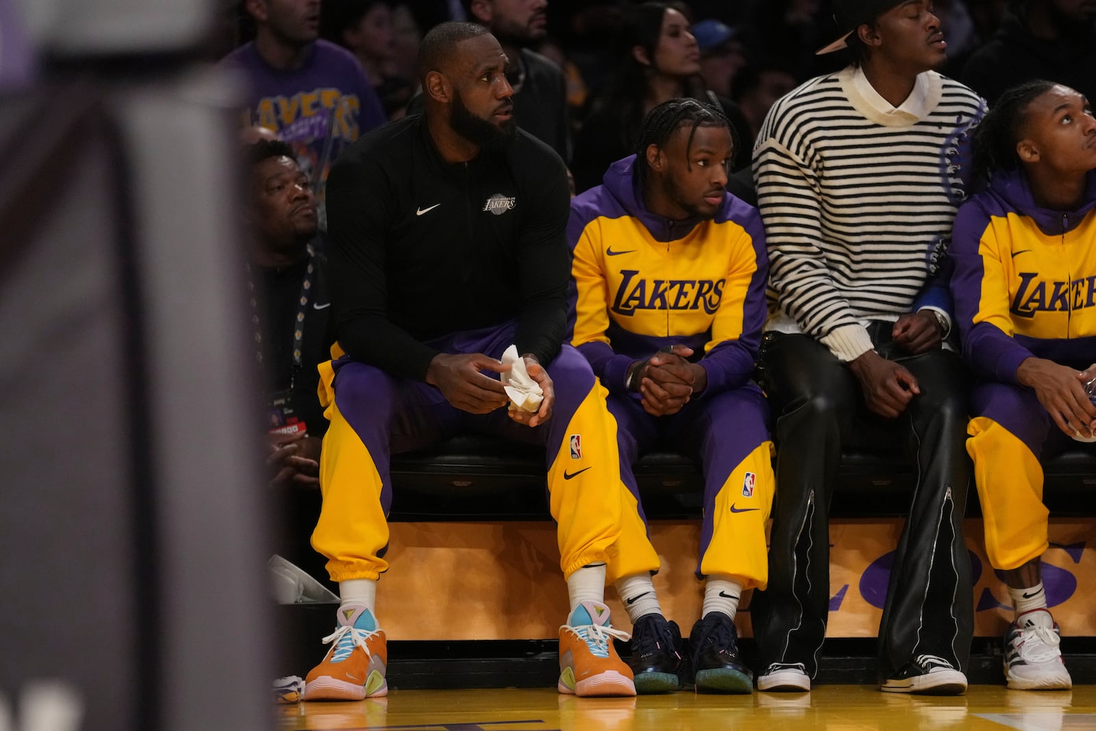 Los Angeles Lakers forward LeBron James (23) guard Bronny James watch play during the first half of an NBA basketball game against the Minnesota Timberwolves, Tuesday, Oct. 22, 2024, in Los Angeles. (AP Photo/Eric Thayer)