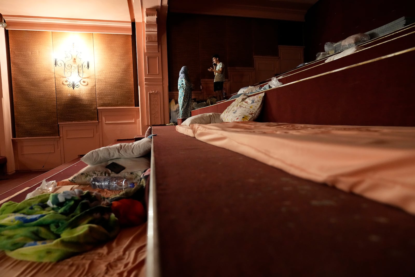 Mona Hanafi, left, a Lebanese woman who fled the ongoing Hezbollah-Israel war in south Lebanon, speaks with her son inside one of Beirut's oldest and best known movie theatres, Le Colisee, in Beirut, Lebanon, Tuesday, Oct. 22, 2024. (AP Photo/Hussein Malla)