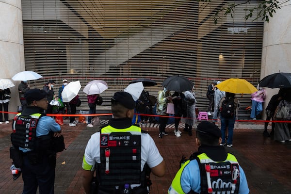 People wait outside the West Kowloon Magistrates' Courts in Hong Kong Tuesday, Nov. 19, 2024, ahead of the sentencing in national security case. (AP Photo/Chan Long Hei)