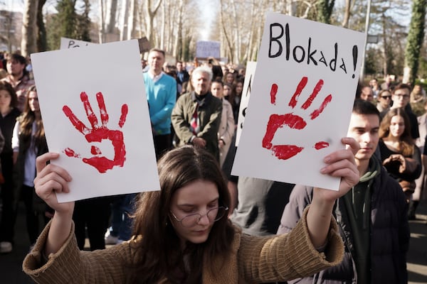 A young woman holds banners during a protest to support Serbian students, in the Bosnian town of Banja Luka, 240 kms northwest of Sarajevo, Friday, Jan. 31, 2025. Banner reads: "Blockade!". (AP Photo/Radivoje Pavicic)