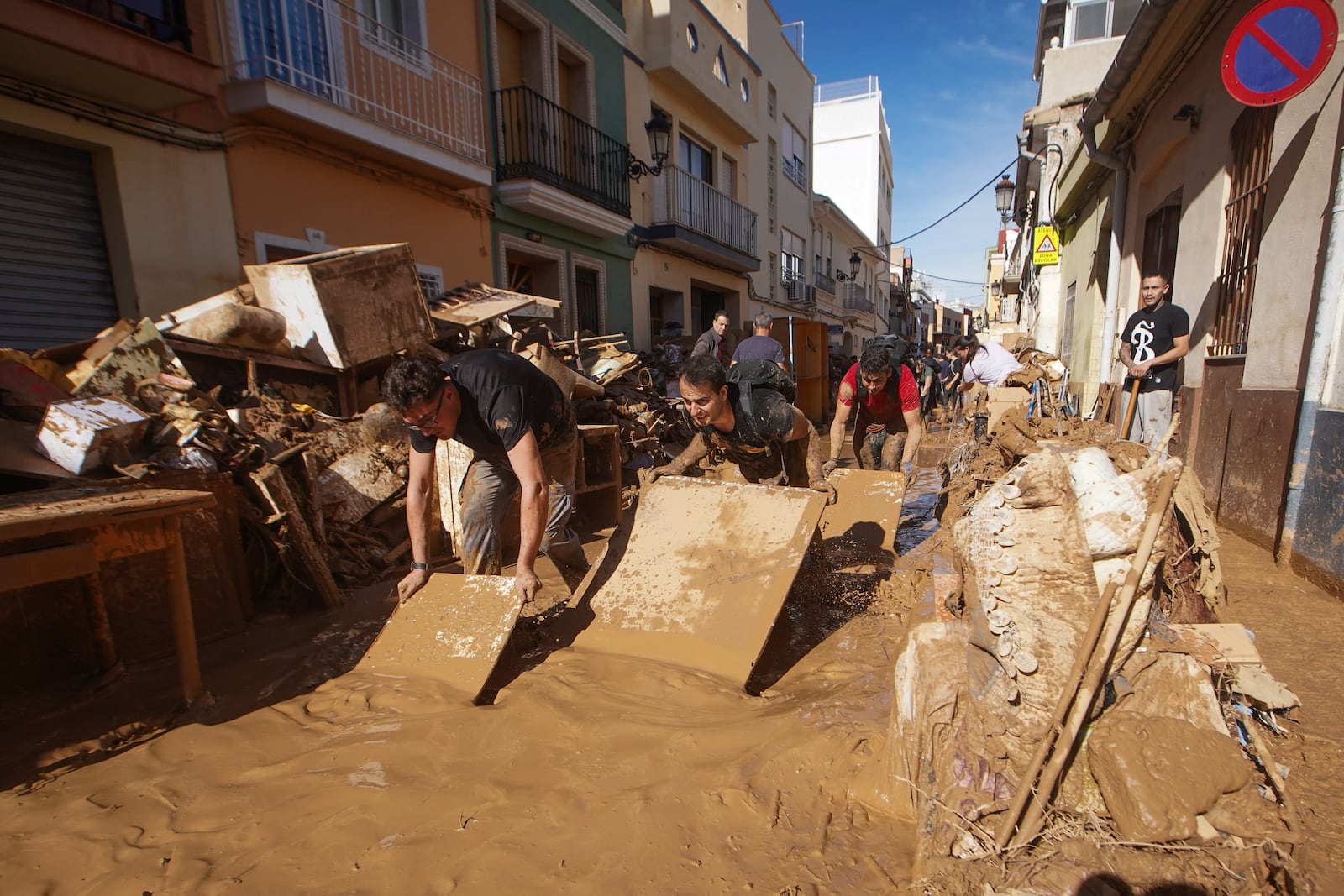 Residents and volunteers try toiling remove mud in an area affected by floods in Paiporta, near Valencia, Spain, Friday, Nov. 1, 2024. (AP Photo/Alberto Saiz)