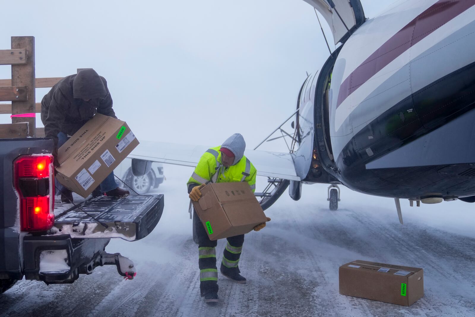 In blizzard winds, Lee Kayotuk, center, helps unload cargo from the one flight of the day in and out of the village in Kaktovik, Alaska, Thursday, Oct. 17, 2024. (AP Photo/Lindsey Wasson)