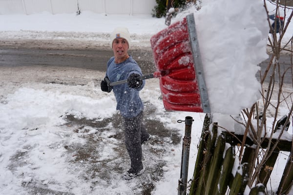 Ben Sisarsky pitches snow over a fence as he clears his girlfriend's parking spot with a borrowed snow shovel in Cincinnati, Tuesday, Jan. 7, 2025. (AP Photo/Carolyn Kaster)