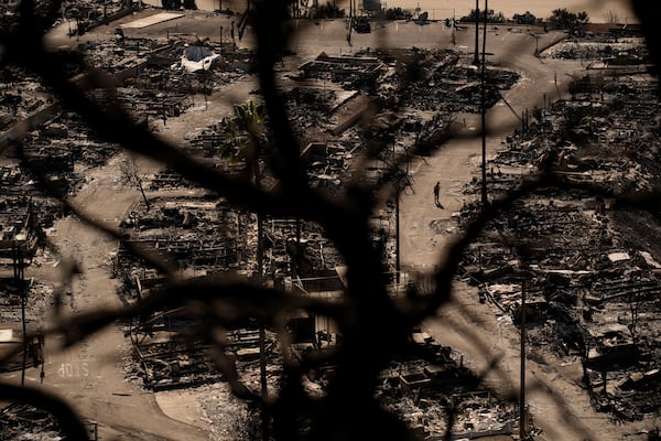 A person walks along a road in a fire-ravaged community in the aftermath of the Palisades Fire in the Pacific Palisades neighborhood of Los Angeles, Monday, Jan. 13, 2025. (AP Photo/John Locher)