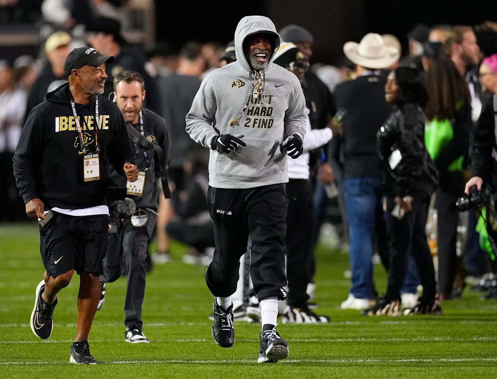 Colorado head coach Deion Sanders, right, jogs around the perimeter of the field with wide receivers coach Jason Phillips as players warm up before an NCAA college football game against Cincinnati Saturday, Oct. 26, 2024, in Boulder, Colo. AP Photo/David Zalubowski)