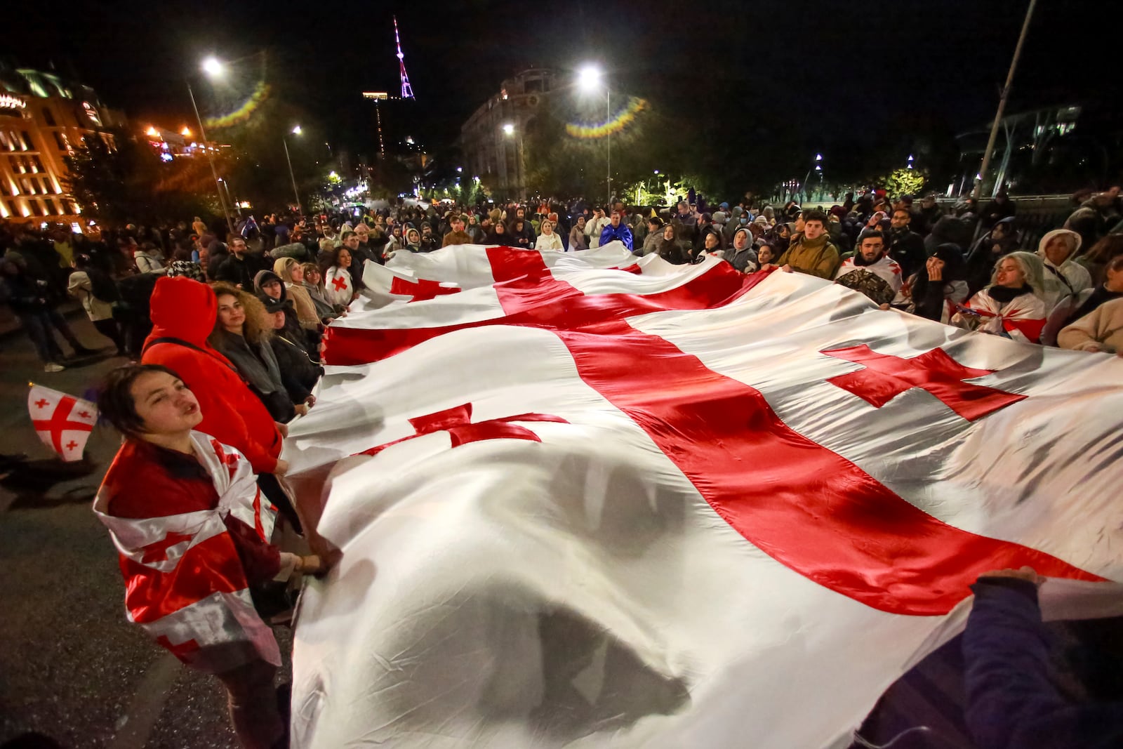 Protesters carry a huge Georgian national flag during a rally against alleged violations in a recent parliamentary election in Tbilisi, Georgia, on Monday, Nov. 4, 2024. (AP Photo/Zurab Tsertsvadze)