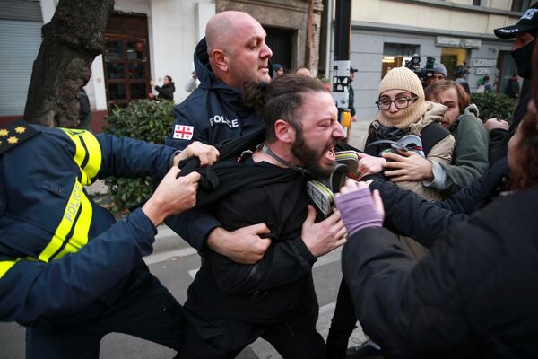 Police try to detain a protester in a street during a rally against the results of the parliamentary elections amid allegations that the vote was rigged in Tbilisi, Georgia, Tuesday, Nov. 19, 2024. (AP Photo/Zurab Tsertsvadze)