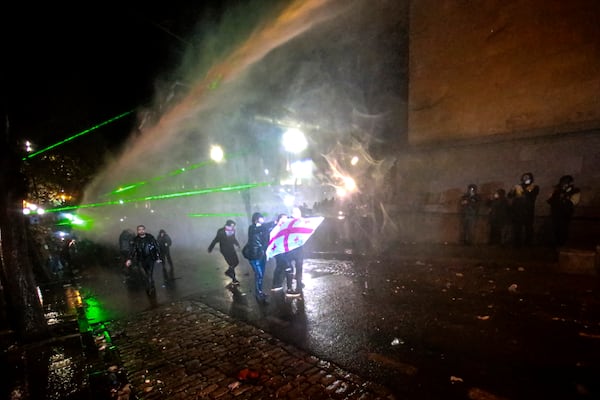 Police use a water cannon to prevent protesters holding a Georgian national flag as they pouring into the streets following Georgian Prime Minister Irakli Kobakhidze's announcement, rallying outside the parliament building in Tbilisi, Georgia, on Friday, Nov. 29, 2024. (AP Photo/Zurab Tsertsvadze)