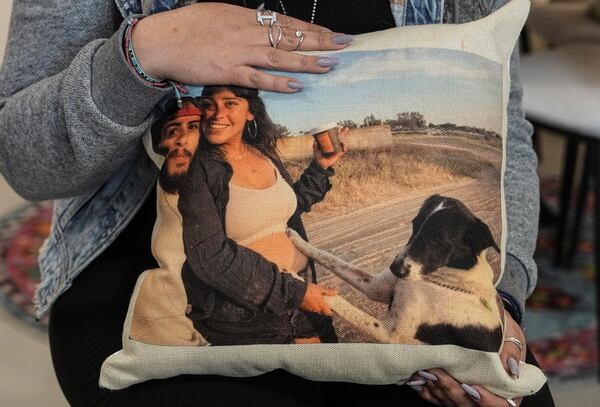 Released hostage Ilana Gritzewsky poses for a portrait in her apartment in Kiryat Gat, Israel, on Sunday, Dec. 15, 2024, while holding a pillow with a photo of herself and her boyfriend, Matan Zangauker, who is being held hostage by Hamas in the Gaza Strip. (AP Photo/Tsafrir Abayov)