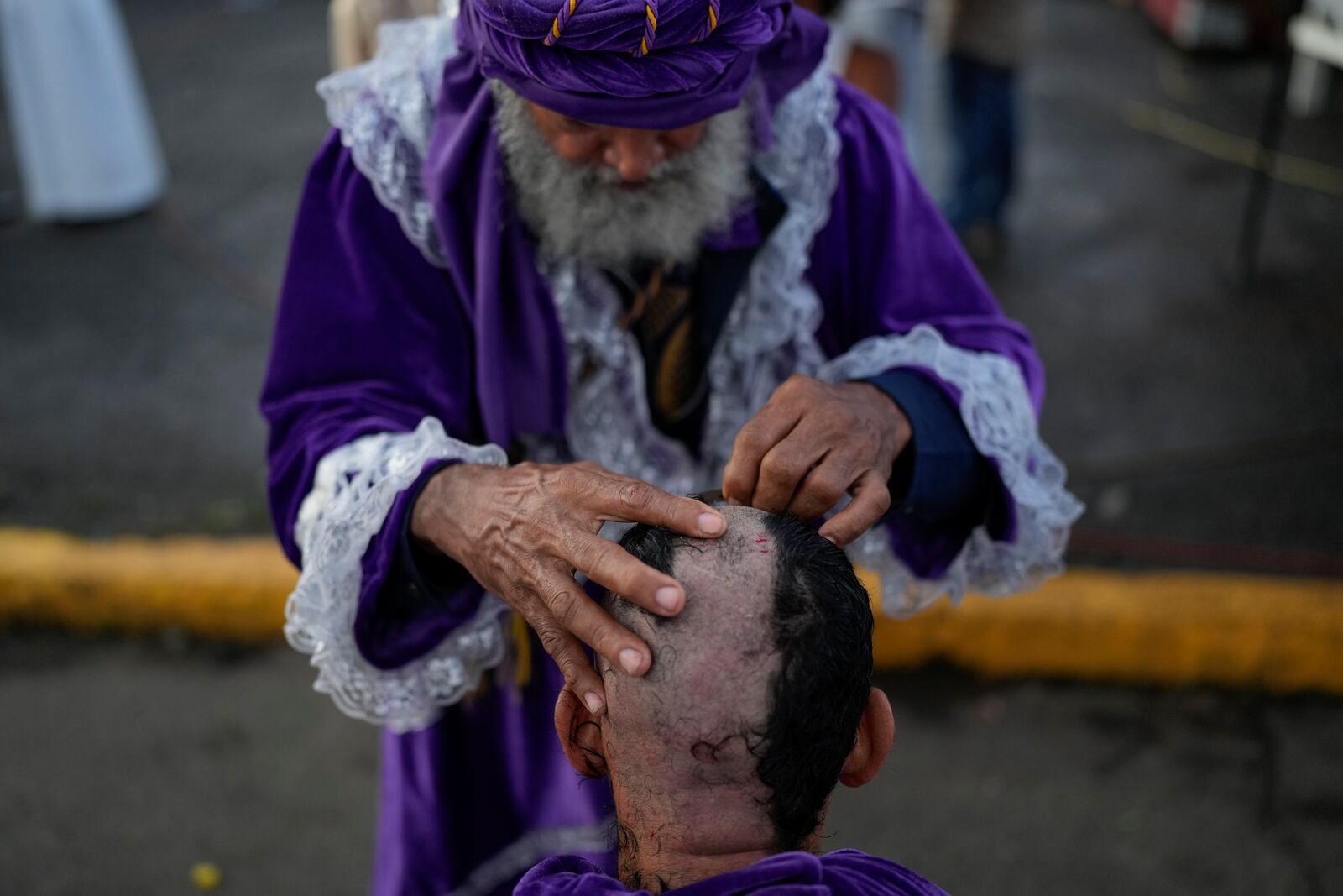 Barber Jose Valdespinto cuts a pilgrim's hair, part of the pilgrim's penance, outside the San Felipe Church to honor the Black Christ in Portobelo, Panama, Monday, Oct. 21, 2024, during a festival celebrating the iconic statue that was found on the shore in 1658. (AP Photo/Matias Delacroix)