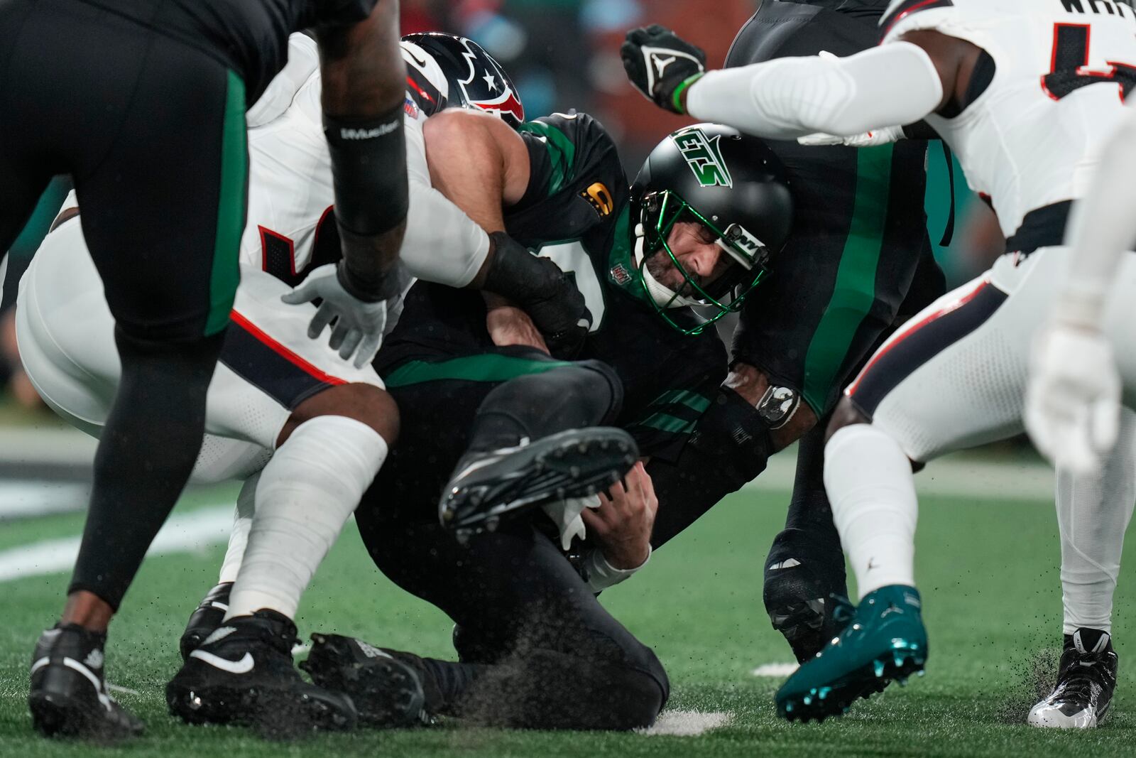 New York Jets quarterback Aaron Rodgers (8) is sacked by Houston Texans defensive end Denico Autry, second from left, during the first half an NFL football game Thursday, Oct. 31, 2024, in East Rutherford, N.J. (AP Photo/Seth Wenig)