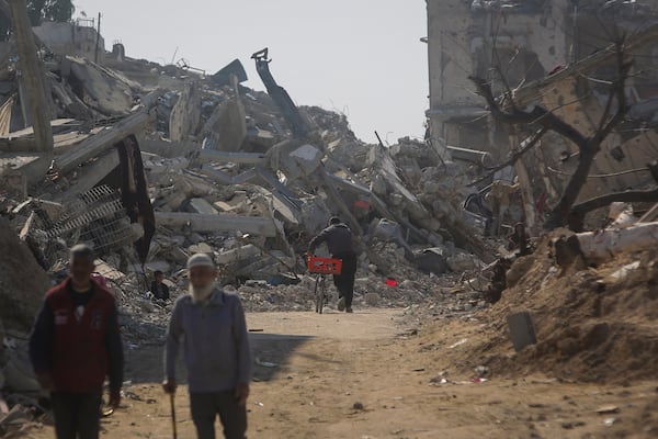 A man pushes his bicycle among the rubble of buildings largely destroyed by Israeli army bombardments in Beit Lahia, northern Gaza Strip, Wednesday, Jan. 29, 2025, after Israel began allowing hundreds of thousands of Palestinians to return to the heavily damaged area last Monday.(AP Photo/Jehaid Alshrafi)