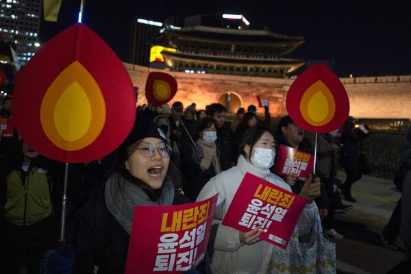 People hold signs with writing reading "Resign Yoon Suk Yeol" and shout slogans as they march to the presidential office after a candlelight vigil against South Korean President Yoon Suk Yeol, in Seoul, South Korea, Wednesday, Dec. 4, 2024 (AP Photo/Ng Han Guan)