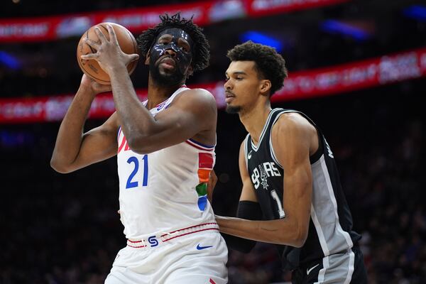 Philadelphia 76ers' Joel Embiid, left, tries to get around San Antonio Spurs' Victor Wembanyama during the first half of an NBA basketball game, Monday, Dec. 23, 2024, in Philadelphia. (AP Photo/Matt Slocum)