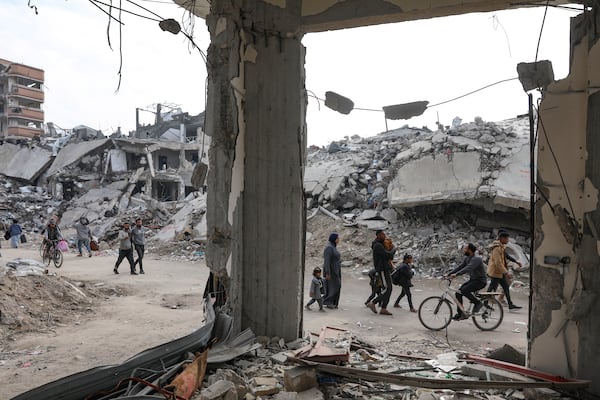 Palestinians walk through the destruction left by the Israeli air and ground offensive on the Gaza Strip, Tuesday, Jan. 28, 2025. (AP Photo/Jehad Alshrafi)