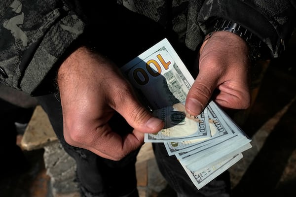 A man poses for a photo without showing his face as he counts U.S. dollars at Ferdowsi street, Tehran's go-to venue for foreign currency exchange, in downtown Tehran, Iran, Wednesday, Dec. 18, 2024. (AP Photo/Vahid Salemi)