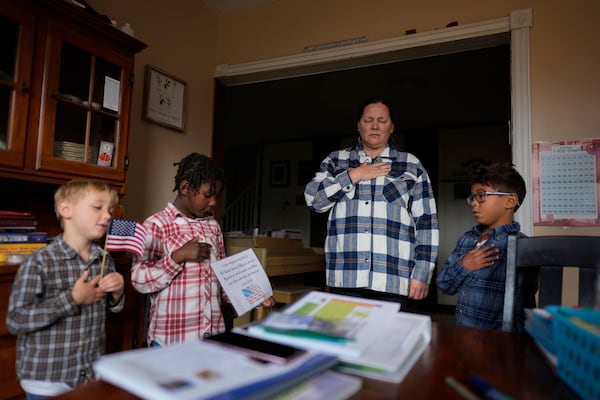 With hands over their hearts, Erin Young and her three adopted children from left, Isaac, 5, Gianna, 7, and Lucas, 8, say the Pledge of Allegiance as they begin their homeschooling lessons, Tuesday, Nov. 12, 2024, in Sunbury, Ohio. (AP Photo/Carolyn Kaster)