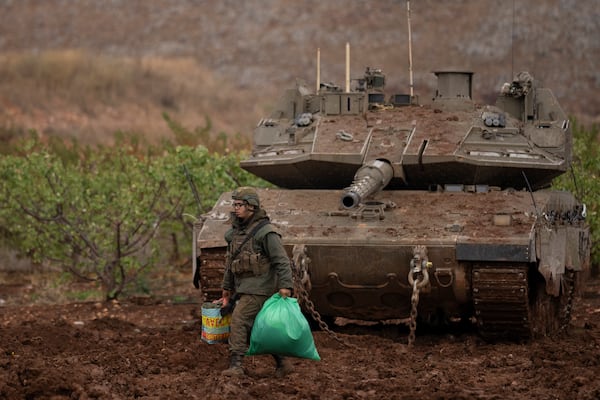 An Israeli soldier walks past a tank on an area near the Israeli-Lebanese border, as seen from northern Israel, Wednesday, Nov. 27, 2024. (AP Photo/Leo Correa)