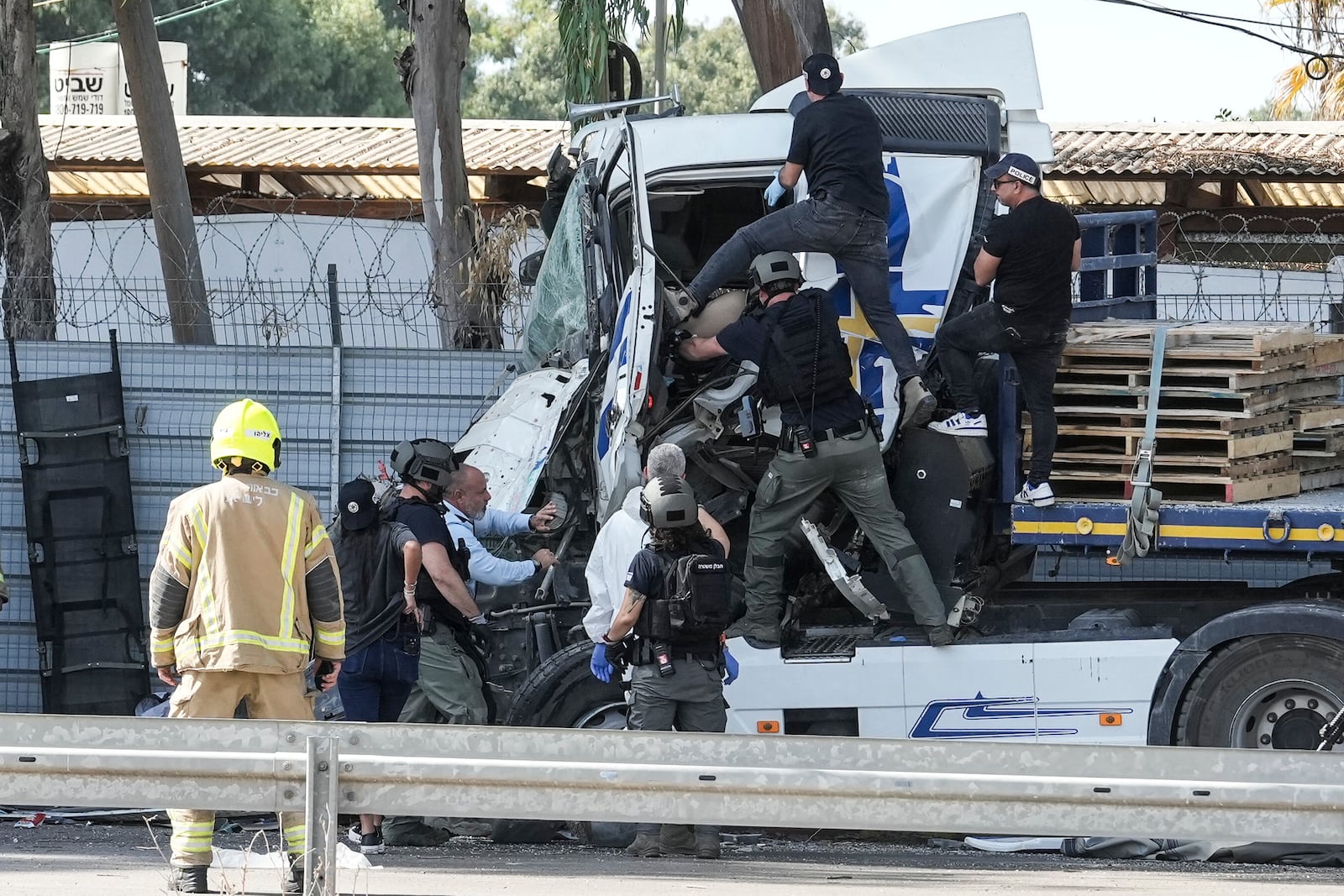 Israeli police climb on a truck to inspect the body of a driver that rammed into a bus stop near the headquarters of Israel's Mossad spy agency, wounding dozens of people, according to Israel's Magen David Adom rescue service in Tel Aviv, Israel, Sunday, Oct. 27, 2024. (AP Photo/Oded Balilty)