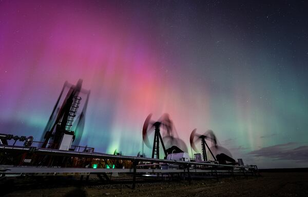 FILE - An aurora borealis, also known as the northern lights, makes an appearance over pumpjacks as they draw out oil and gas from well heads near Cremona, Alberta, Thursday, Oct. 10, 2024. (Jeff McIntosh/The Canadian Press via AP, File)