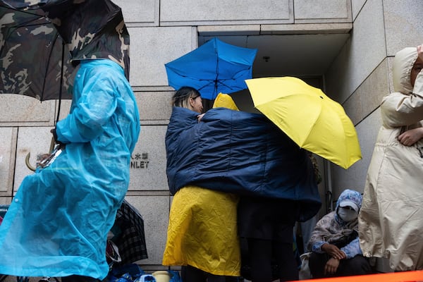 People wait outside the West Kowloon Magistrates' Courts in Hong Kong Tuesday, Nov. 19, 2024, ahead of the sentencing in national security case. (AP Photo/Chan Long Hei)