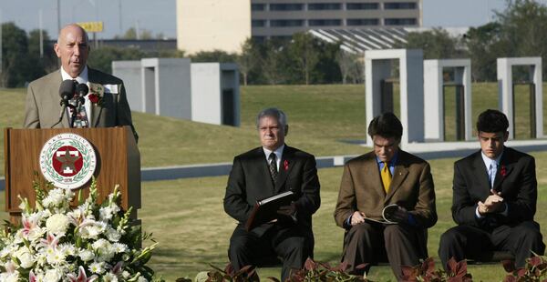 FILE - Jerry Ebanks, left, whose son Michael Ebanks was killed in the 1999 bonfire collapse, speaks at the Bonfire Memorial dedication at Texas A&M University in College Station, Nov. 18, 2004. In back from left to right is University President Dr. Robert M. Gates; Texas Gov. Rick Perry; and Student Body President Jackson Hildebrand. (AP Photo/Donna McWilliam, File)