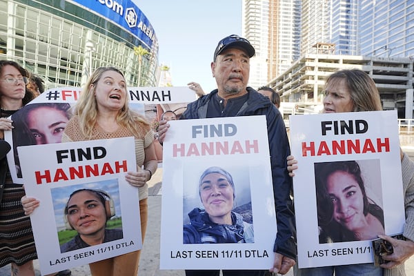 Ryan Kobayashi, center, holds a picture of his missing daughter Hannah Kobayashi outside Crypto.com Arena, Thursday, Nov. 21, 2024 in Los Angeles. (AP Photo/Damian Dovarganes)