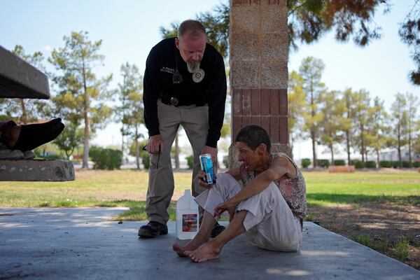 FILE - Mark Paulson, a Public Response and Code Enforcement officer, checks on Deb Billet, 66, before calling an ambulance to take her to a hospital for heat-related symptoms, July 10, 2024, in Henderson, Nev. (AP Photo/John Locher, File)