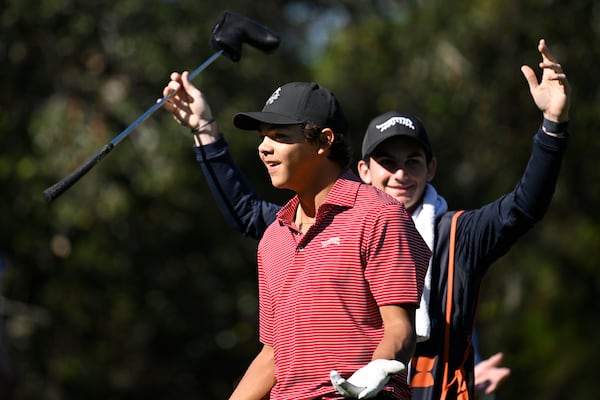 Charlie Woods, front, and his caddie Luke Wise react after his hole-in-one on the fourth hole during the final round of the PNC Championship golf tournament, Sunday, Dec. 22, 2024, in Orlando, Fla. (AP Photo/Phelan M. Ebenhack)