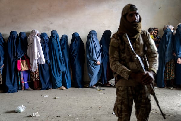 FILE - A Taliban fighter stands guard as women wait to receive food rations distributed by a humanitarian aid group in Kabul, Afghanistan, May 23, 2023. (AP Photo/Ebrahim Noroozi, File)