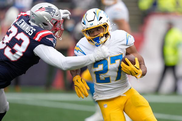 Los Angeles Chargers running back J.K. Dobbins (27) tries to break away from New England Patriots linebacker Anfernee Jennings (33) during the first half of an NFL football game, Saturday, Dec. 28, 2024, in Foxborough, Mass. (AP Photo/Robert F. Bukaty)