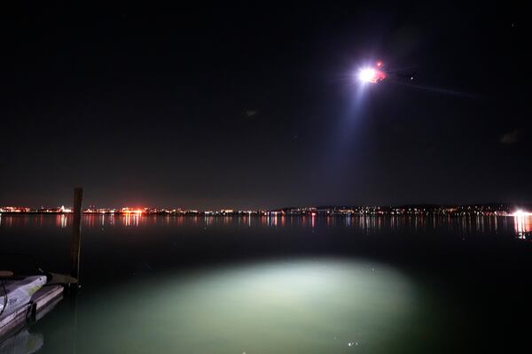 A helicopter uses a spotlight on the Potomac River near Ronald Reagan Washington National Airport, Thursday, Jan. 30, 2025, in Arlington, Va. (AP Photo/Alex Brandon)