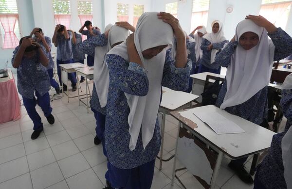 Students cover their head during an earthquake drill at a school in Banda Aceh, Indonesia, Thursday, Dec. 12, 2024. (AP Photo/Achmad Ibrahim)