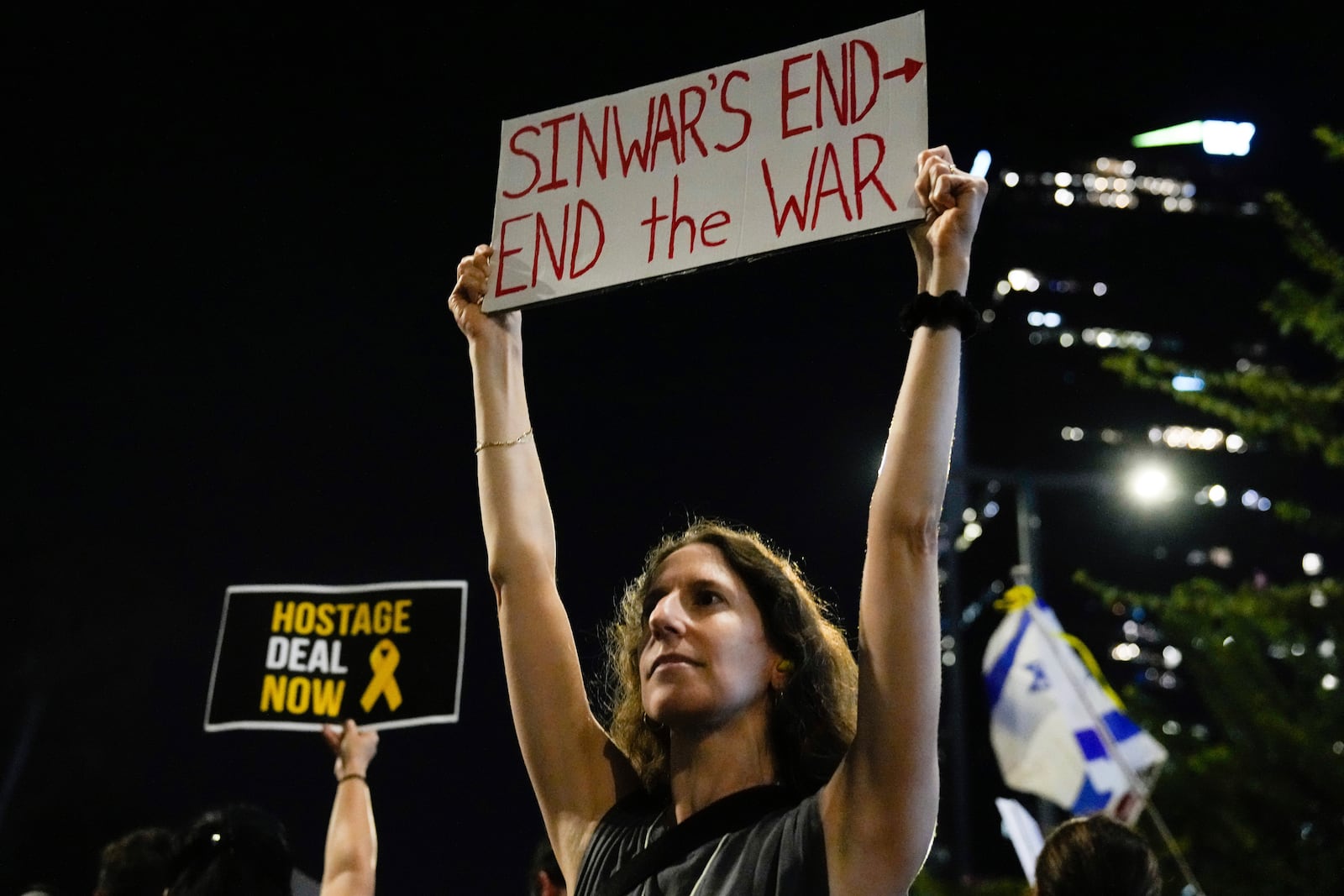 A demonstrator holds a sign about the killing of Hamas leader Yahya Sinwar during a protest calling for a cease-fire deal and the immediate release of hostages held by Hamas on Thursday, Oct. 17, 2024, in Tel Aviv, Israel. (AP Photo/Ariel Schalit)