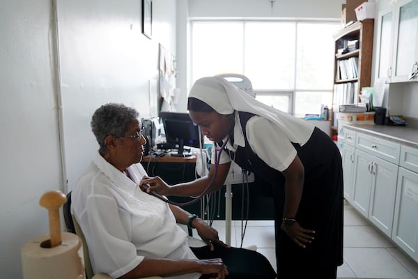 Sister Seyram Mary Adzokpa, right, listens to Sister Clara Mae Jackson's heart in the motherhouse of the Sisters of the Holy Family in New Orleans, Tuesday, June 25, 2024. (AP Photo/Jessie Wardarski)