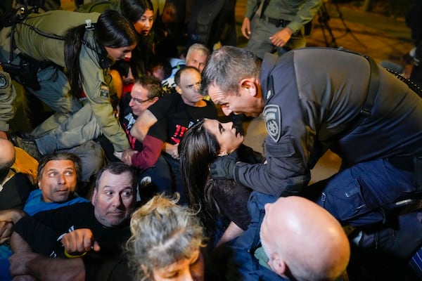 A police officer shouts at a woman as people protesting against Prime Minister Benjamin Netanyahu's government and calling for the release of hostages held in the Gaza Strip by the Hamas militant group, are dispersed near the Prime Minister's residence in Jerusalem, Monday, Oct. 28, 2024. (AP Photo/Ohad Zwigenberg)