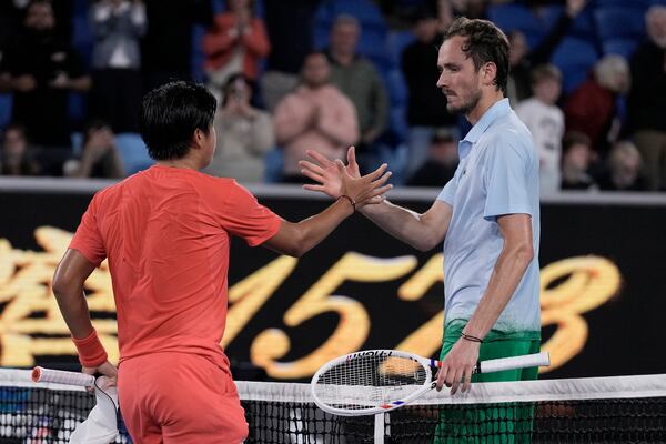 Learner Tien of the U.S. is congratulated after winning his second round match against Daniil Medvedev of Russia, right, at the Australian Open tennis championship in Melbourne, Australia, in the early hours of Friday, Jan. 17, 2025. (AP Photo/Ng Han Guan)