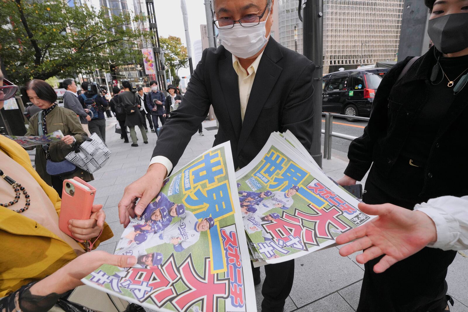 A staff member distributes copies of an extra edition of the Sports Nippon newspaper in Tokyo, Thursday, Oct. 31, 2024, reporting on the Los Angeles Dodgers' victory in the World Series baseball match after the Dodgers defeated the New York Yankees in Game 5 in New York. (AP Photo/Eugene Hoshiko)