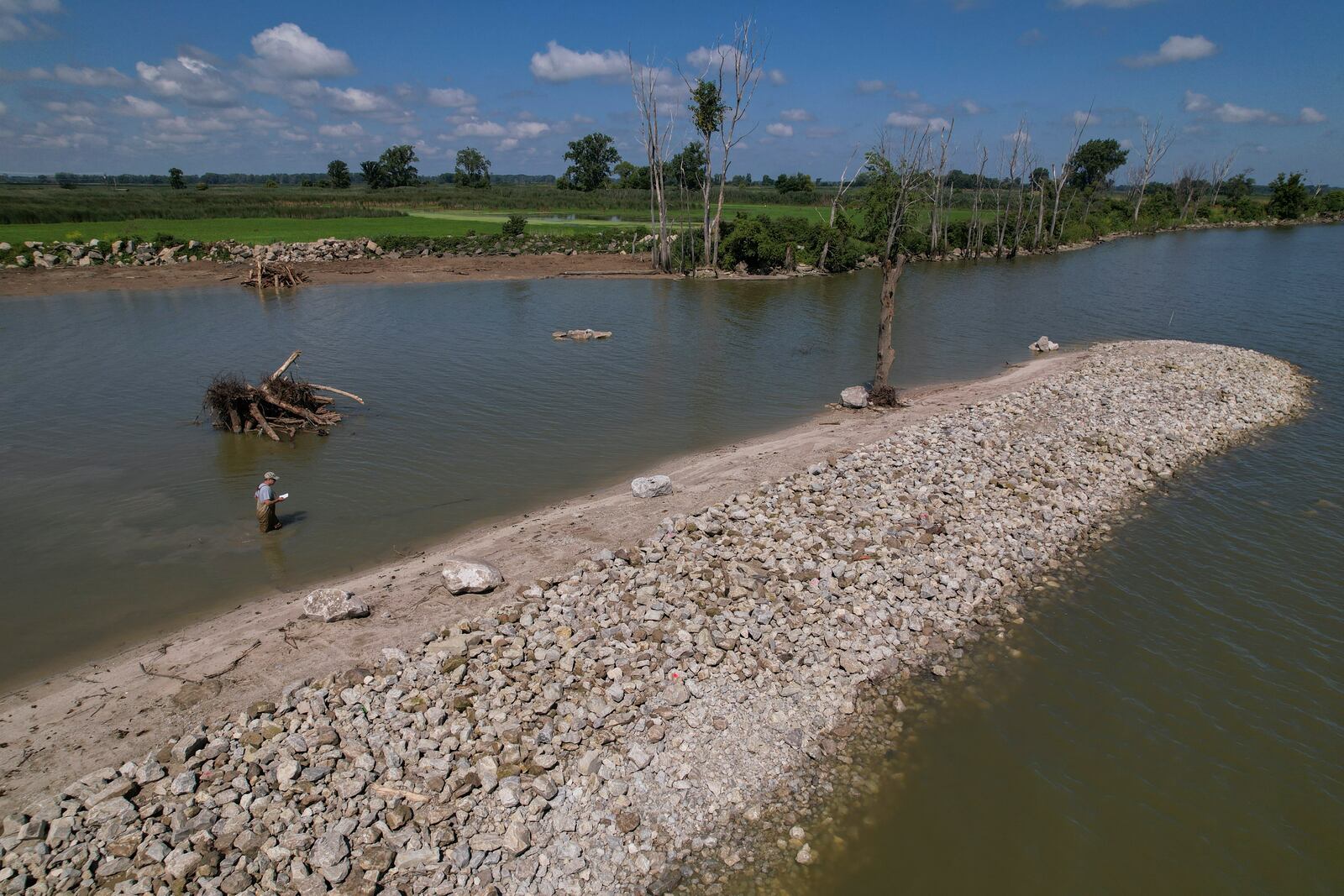 Matthew Kovach, a wetland ecologist, surveys the area near a human-made rock barrier in Sandusky Bay, Thursday, July 11, 2024, in Vickery, Ohio. (AP Photo/Joshua A. Bickel)